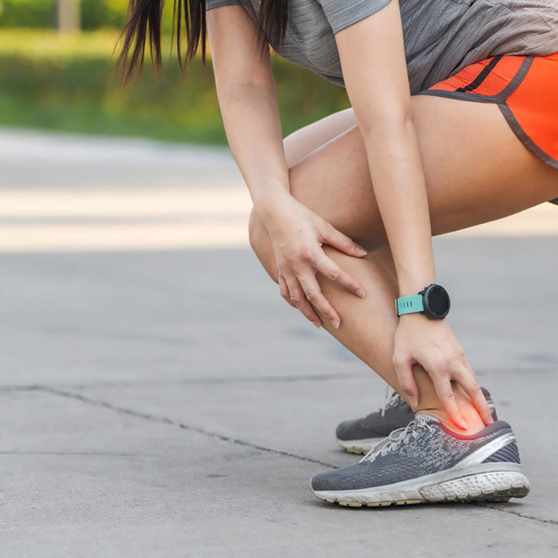 Woman in sports clothes, clutching archilles tendon