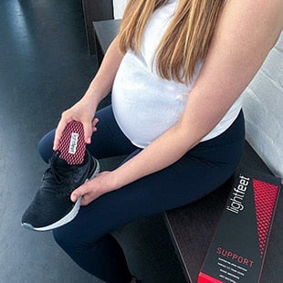 Pregnant woman putting insole into sports shoe