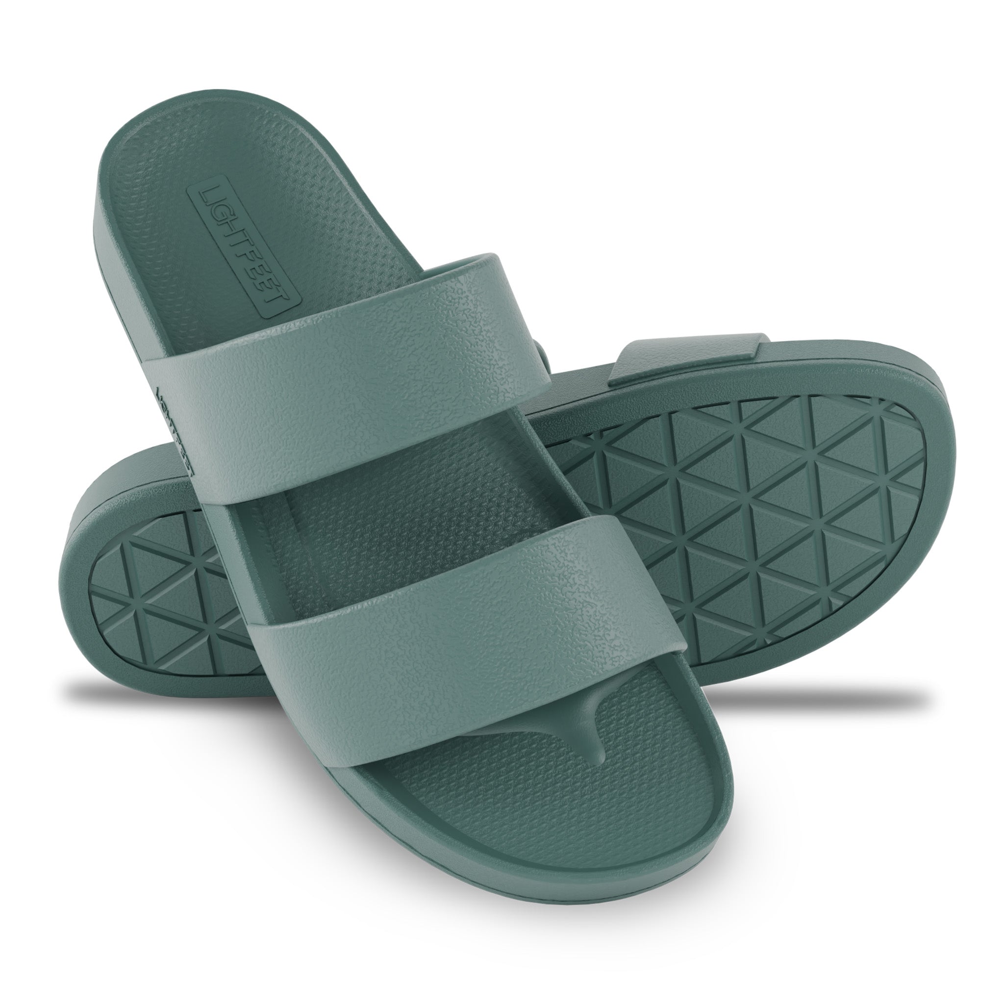 Pair of green slides with a textured sole on a white background