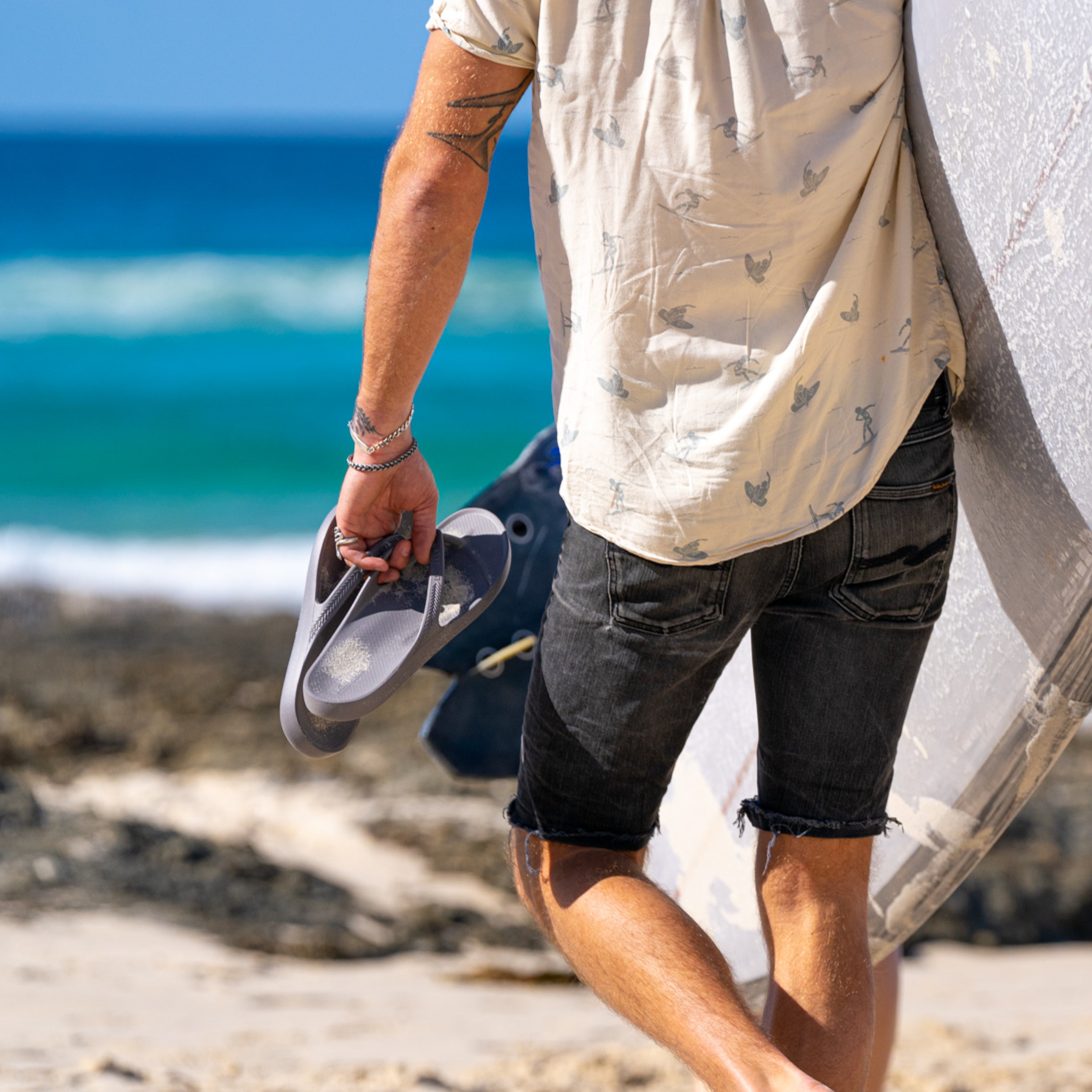 Person holding Lightfeet Arch Support Thongs on a beach with ocean in the background